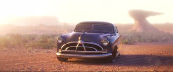 Movie still from “Cars 3” (2017), directed by Brian Fee – An old car parked in the dirt near a field; Wide shot, High angle