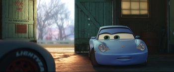 Movie still from “Cars 3” (2017), directed by Brian Fee – A blue car is parked in front of a barn door; Medium shot, Low angle