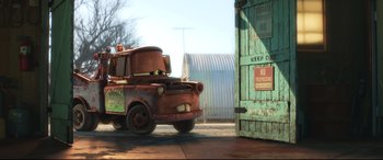 Movie still from “Cars 3” (2017), directed by Brian Fee – An old rusty truck is parked in front of a door; Wide shot, Low angle