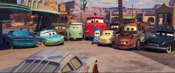 Movie still from “Cars 3” (2017), directed by Brian Fee – A group of cartoon cars parked in a parking lot; Wide shot, High angle