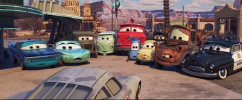Movie still from “Cars 3” (2017), directed by Brian Fee – A group of cars are parked on the side of the road; Wide shot, Low angle