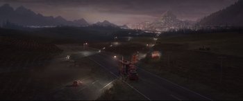 Movie still from “Cars 3” (2017), directed by Brian Fee – A truck driving down a road near a city at night time; Extreme Wide shot, High angle