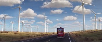 Movie still from “Cars 3” (2017), directed by Brian Fee – A truck driving down a road near some wind mills; Extreme Wide shot, Low angle