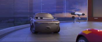 Movie still from “Cars 3” (2017), directed by Brian Fee – A car that is sitting in a building; Medium shot, Low angle
