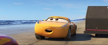 Movie still from “Cars 3” (2017), directed by Brian Fee – A yellow car is on the beach near the water; Medium shot, Low angle