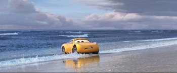 Movie still from “Cars 3” (2017), directed by Brian Fee – A yellow car driving through the water on the beach; Extreme Wide shot, Low angle