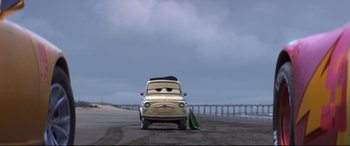 Movie still from “Cars 3” (2017), directed by Brian Fee – An old yellow van with a green umbrella on the road; Wide shot, Low angle