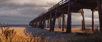 Movie still from “Cars 3” (2017), directed by Brian Fee – A wooden pier on the beach under a cloudy sky; Extreme Wide shot, Low angle