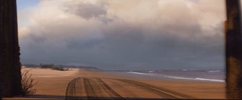 Movie still from “Cars 3” (2017), directed by Brian Fee – A view of a beach from a distance with a cloudy sky above it; Extreme Wide shot, High angle