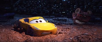 Movie still from “Cars 3” (2017), directed by Brian Fee – A yellow toy car in the dirt near a pile of tires; Wide shot, High angle