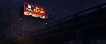 Movie still from “Cars 3” (2017), directed by Brian Fee – A billboard that reads " time to re - tire ?" on the side of a highway; Extreme Wide shot, Low angle