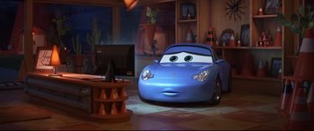 Movie still from “Cars 3” (2017), directed by Brian Fee – A blue car is in a living room; Wide shot, High angle