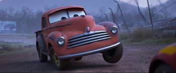 Movie still from “Cars 3” (2017), directed by Brian Fee – A red car is driving down a dirt road; Wide shot, Low angle