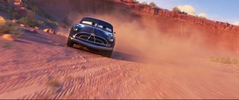 Movie still from “Cars 3” (2017), directed by Brian Fee – A car driving down a dirt road in the middle of the desert; Wide shot, Low angle