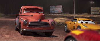 Movie still from “Cars 3” (2017), directed by Brian Fee – A red car and a yellow car in a dirt field; Medium shot, Low angle