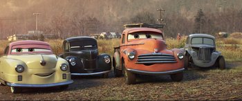 Movie still from “Cars 3” (2017), directed by Brian Fee – Two cars are parked next to each other on the grass; Wide shot, Low angle