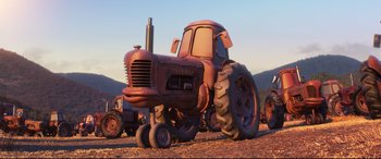 Movie still from “Cars 3” (2017), directed by Brian Fee – An old tractor is parked in the dirt; Wide shot, Low angle