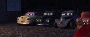 Movie still from “Cars 3” (2017), directed by Brian Fee – A group of old cars that are sitting in the dirt; Wide shot, High angle