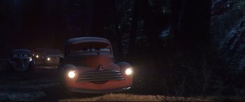 Movie still from “Cars 3” (2017), directed by Brian Fee – An old red car driving down a road at night; Wide shot, Low angle