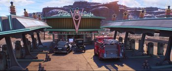 Movie still from “Cars 3” (2017), directed by Brian Fee – An old fashioned gas station with cars parked in front of it; Extreme Wide shot, High angle