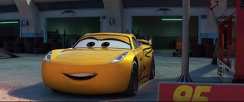 Movie still from “Cars 3” (2017), directed by Brian Fee – A yellow race car is parked in a parking lot; Medium shot, Low angle