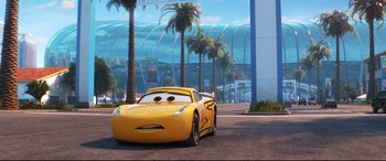 Movie still from “Cars 3” (2017), directed by Brian Fee – A yellow sports car is parked in front of palm trees; Wide shot, Low angle