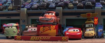 Movie still from “Cars 3” (2017), directed by Brian Fee – A group of toy cars in front of a building; Wide shot, Low angle