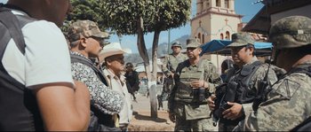 Movie still from “Cartel Land” (2015), directed by Matthew Heineman – A group of men standing around a tree; Medium shot, Over the shoulder angle