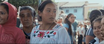 Movie still from “Cartel Land” (2015), directed by Matthew Heineman – A woman wearing a white dress with red flowers; Close Up shot, Over the shoulder angle