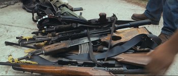 Movie still from “Cartel Land” (2015), directed by Matthew Heineman – A bunch of different types of guns laying on the ground; Medium shot, High angle