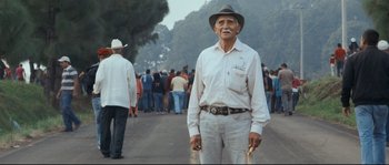 Movie still from “Cartel Land” (2015), directed by Matthew Heineman – An older man in a white shirt and a hat is standing in front of a group of people; Medium shot, Low angle