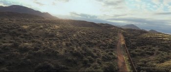 Movie still from “Cartel Land” (2015), directed by Matthew Heineman – An aerial view of a dirt road in the middle of the desert; Extreme Wide shot, High angle