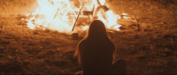 Movie still from “Cartel Land” (2015), directed by Matthew Heineman – A woman sitting in front of a fire; Medium shot, High angle