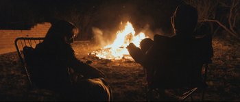 Movie still from “Cartel Land” (2015), directed by Matthew Heineman – Two people sitting in front of a fire at night; Wide shot, Over the shoulder angle