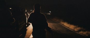 Movie still from “Cartel Land” (2015), directed by Matthew Heineman – A person walking down a street at night; Medium shot, Low angle