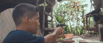 Movie still from “Cartel Land” (2015), directed by Matthew Heineman – A man holding a gun in his hand; Medium shot, Over the shoulder angle