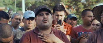 Movie still from “Cartel Land” (2015), directed by Matthew Heineman – A group of men standing around each other holding their hands on their chest; Medium shot, Low angle