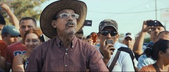 Movie still from “Cartel Land” (2015), directed by Matthew Heineman – A man wearing a hat and holding a cell phone in his hand; Medium shot, Low angle