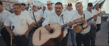 Movie still from “Cartel Land” (2015), directed by Matthew Heineman – A group of men standing next to each other holding guitars; Medium shot, Low angle