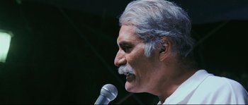 Movie still from “Cartel Land” (2015), directed by Matthew Heineman – An older man is speaking into a microphone; Close Up shot, Low angle