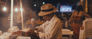 An old man wearing a straw hat and a white shirt