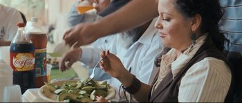 Movie still from “Cartel Land” (2015), directed by Matthew Heineman – A woman eating a plate of food at a table; Medium shot, Over the shoulder angle