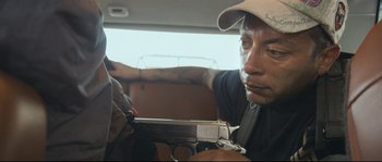 Movie still from “Cartel Land” (2015), directed by Matthew Heineman – A man holding a gun while sitting in the back of a car; Close Up shot, Low angle