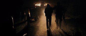 Movie still from “Cartel Land” (2015), directed by Matthew Heineman – A group of people walking down a street at night; Wide shot, Over the shoulder angle