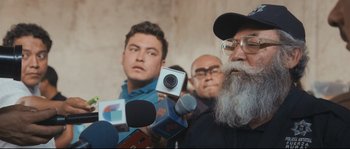 Movie still from “Cartel Land” (2015), directed by Matthew Heineman – A man with a beard is being interviewed by reporters; Close Up shot, Over the shoulder angle