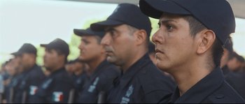 Movie still from “Cartel Land” (2015), directed by Matthew Heineman – A group of men in black uniforms are standing together; Close Up shot, Over the shoulder angle
