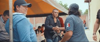 Movie still from “Cartel Land” (2015), directed by Matthew Heineman – A man shaking hands with another man holding a gun; Medium shot, Over the shoulder angle