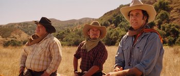 Movie still from “Casa de mi Padre” (2012), directed by Matt Piedmont – A group of men sitting in a field wearing cowboy hats and bandannas; Medium shot, Over the shoulder angle