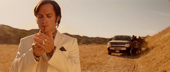 Movie still from “Casa de mi Padre” (2012), directed by Matt Piedmont – A man in a white suit standing next to a truck in a field; Close Up shot, Low angle