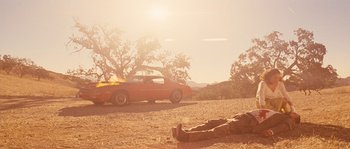 Movie still from “Casa de mi Padre” (2012), directed by Matt Piedmont – An orange car parked on the side of a road; Wide shot, Low angle